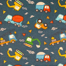 A flannel fabric swatch featuring assorted colorful construction vehicles tossed on a navy background. 