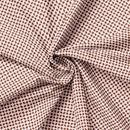 A folded view of a cotton fabric featuring coffee beans on a light pink background. It is carefully folded to show the weight of the fabric. 