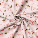 Fabric patterned with bows, espresso martinis, hearts, and coffee beans on a light pink background. It has been carefully folded to show he weight of the fabric. 