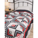 A quilted bedspread featuring a variation on the log cabin block in white, red, and black. 