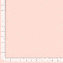 A close-up of a pale pink fabric or material swatch with a scattered white alphabet pattern, shown with ruler markings along the left and bottom edges.