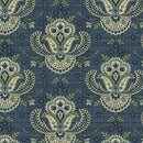A close-up of a repeating paisley pattern on fabric or wallpaper, featuring ornate medallion motifs in cream, sage green, and blue on a dark blue textured background.