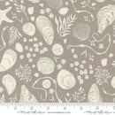 pattern of assorted white shells, sand dollars, and seaweed on a gray background with a moda branded ruler for scale