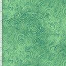 A close-up of a green patterned fabric with a repeating swirl motif and a white ruler scale visible along the left edge.