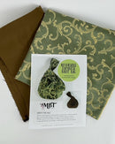 An example of the front cover of the Reversible Japanese Knot Bag Pattern alongside the brown and green fabrics available in the kit for the class. 