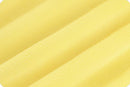 A close-up of a soft, textured yellow fabric with diagonal folds.