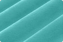 A close-up of a soft, textured fabric in a bright turquoise or aqua color, showing diagonal folds and a plush surface.