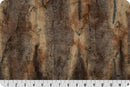 A  faux fur fabric featuring a pattern reminiscent of a red fox, with a gradient from amber to brown to black. There is a ruler at the bottom to show the scale of  the pattern. 