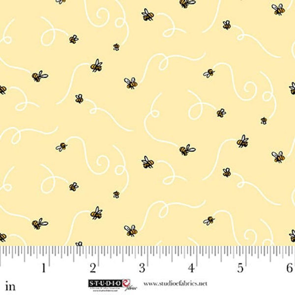 Fabric with bee pattern on a yellow background, ruler for scale