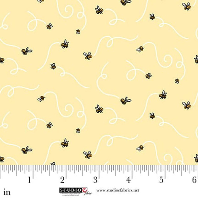 Fabric with bee pattern on a yellow background, ruler for scale