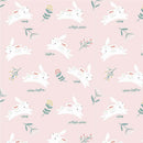 Fabric swatch patterned with white bunnies jumping and small bundles of flowers on a light pink background. 