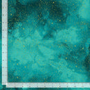 Fabric swatch patterned with a painterly teal night sky speckled with gold metallic stars. 